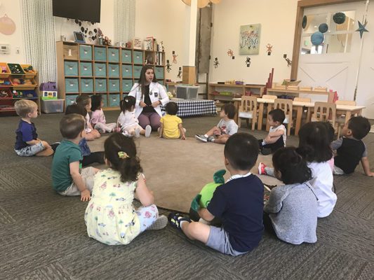 Children working with Montessori sandpaper letters, learning to trace and sound out words.