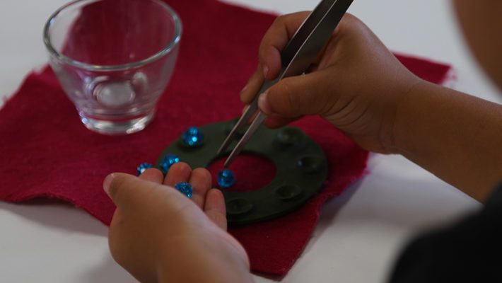 Children working with Montessori sandpaper letters, learning to trace and sound out words.